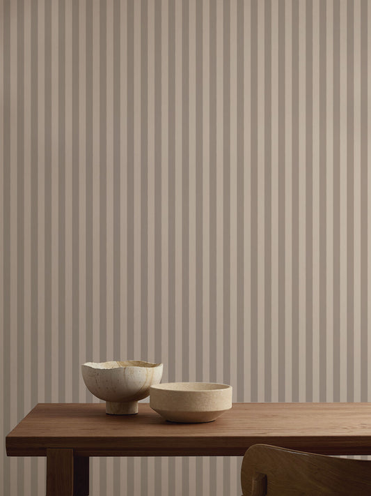 Papel mural Archie Warm Brown, cálido diseño de rayas verticales continuas en gris topo y crema suave. Ideal para baños y cocinas.