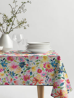 Mantel de hule Multicolor Flowers Zinnias Garden con flores de acuarela en fucsia, azul y amarillo, sobre una mesa de comedor