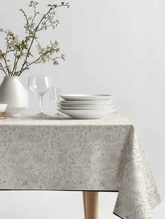 Mantel de hule Paisely con flores y motivos de cachemira en beige y crema, sobre una mesa de comedor