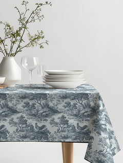 Mantel de hule Rooster con escenas campestres de gallos y árboles en azul grisáceo y blanco, sobre una mesa de comedor