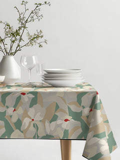 Mantel de hule Sopiva con flores grandes estilizadas en crema, verde salvia y beige, sobre una mesa de comedor