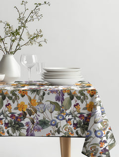 Mantel de hule Summer Dreams V con flores botánicas en naranjo, morado y azul, sobre una mesa de comedor