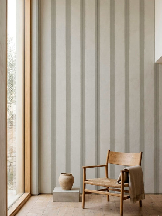 Papel mural Henry Beige, sutil diseño de grupos de rayas verticales en gris claro y blanco roto. Ideal para baños y cocinas.