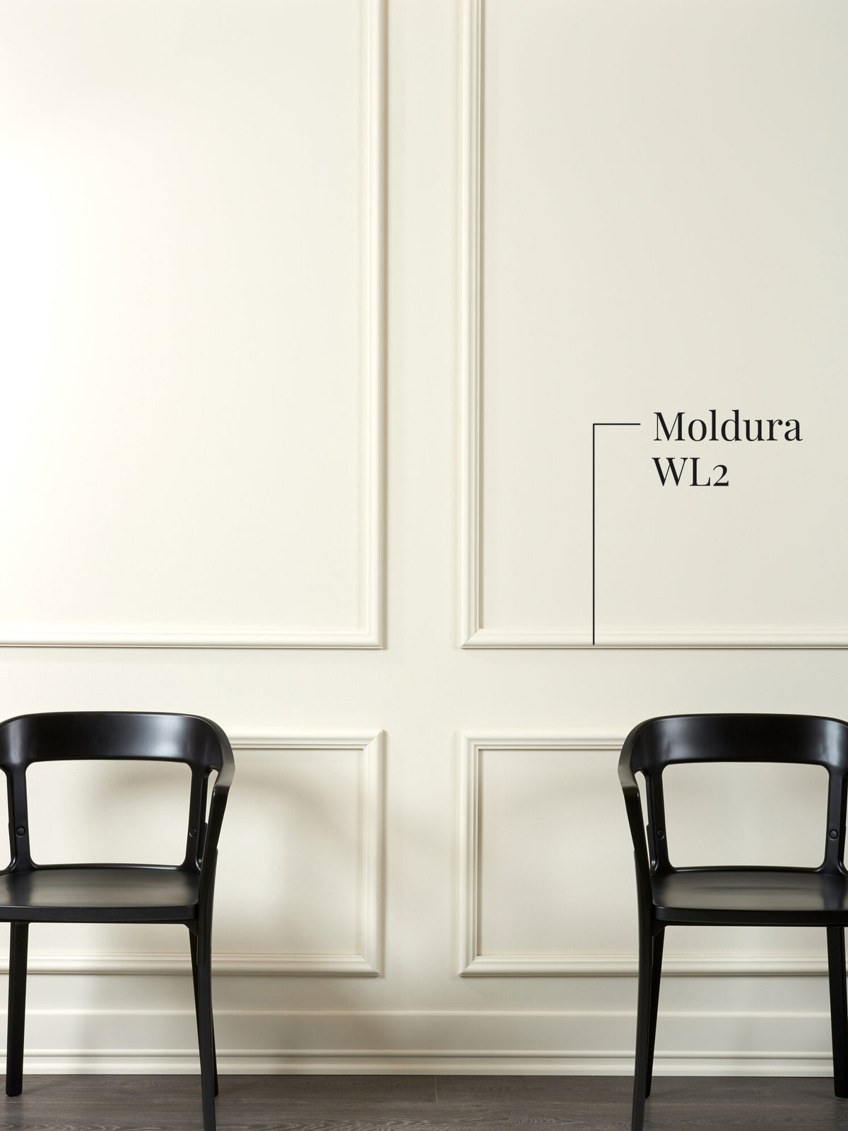 Moldura muro WL2 dibujando cuarterones en un muro blanco, con dos sillas negras delante