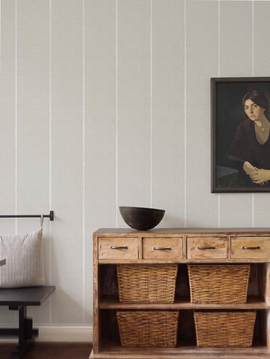 Papel mural Albert Beige, minimalista diseño de rayas verticales finas en blanco sobre beige claro texturado.