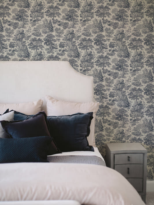 Papel mural Moulin Blue, clásico diseño de toile de Jouy azul sobre crema con bosques y pinos a plumilla.